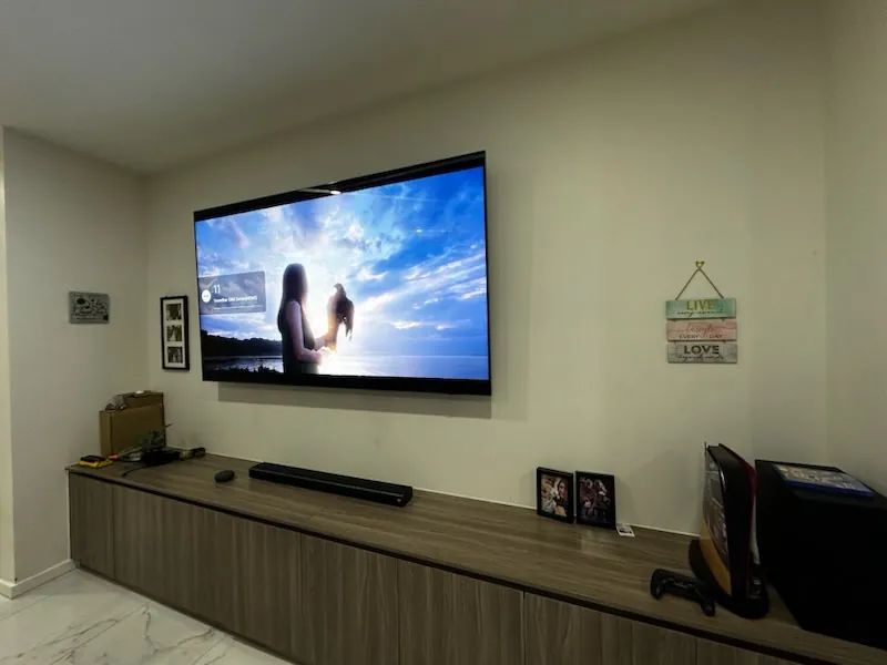 Large TV mounted above a timber cabinet with soundbar